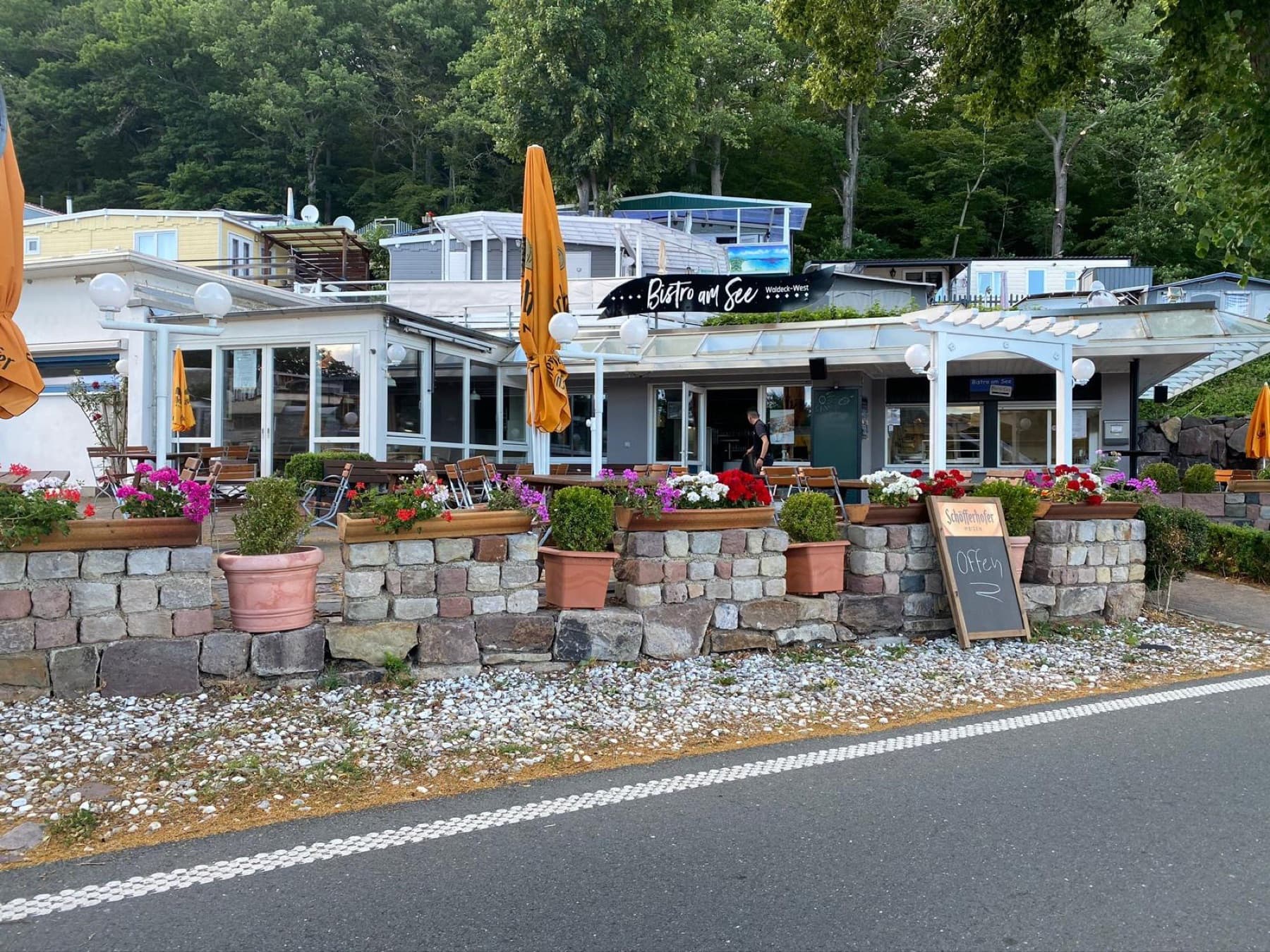 Das Bistro von der Straße aus mit Blumen und Kreidetafel