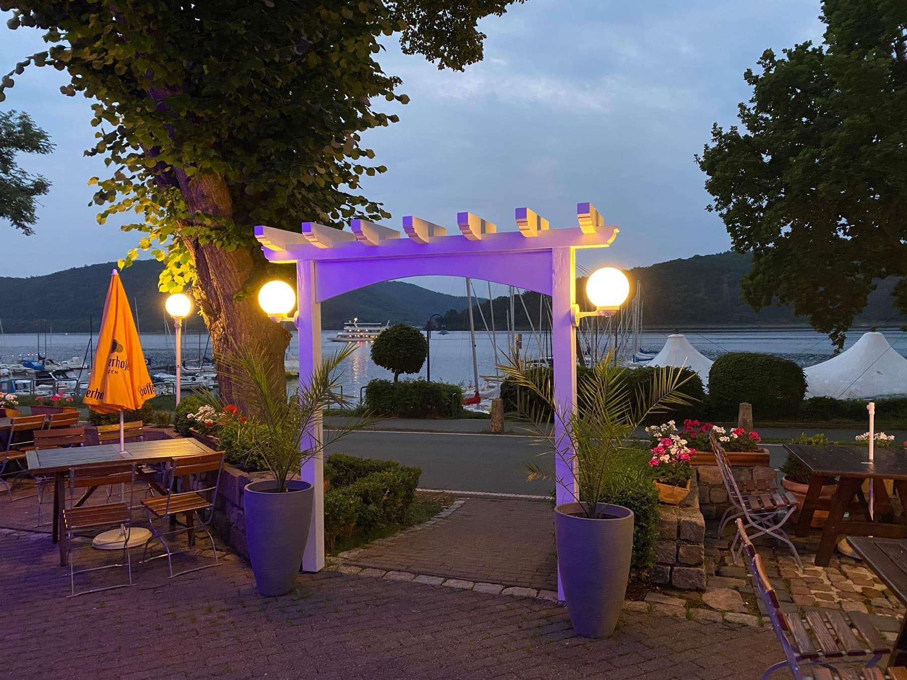 Beleuchtete Pergola auf der Terrasse am Abend, dahinter der Edersee