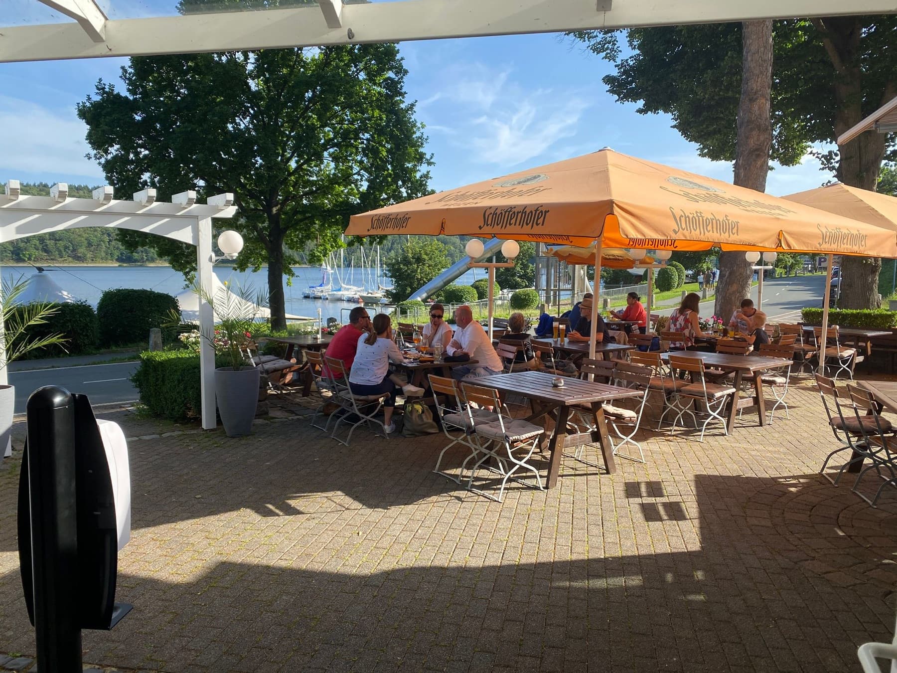 Gäste auf der Terrasse unter orangen Sonnenschirmen